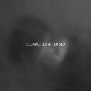 X's by Cigarettes After Sex album cover. The logo for the band Cigarettes After Sex in white font against a blurry black and white background vaguely depicting a man and woman kissing.